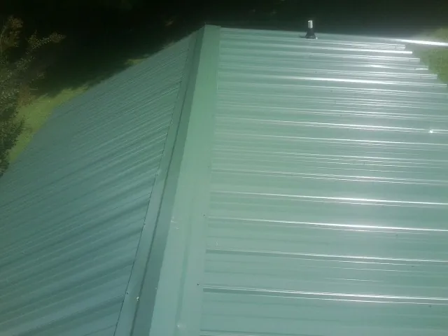 New green metal panels meeting at the ridge of a roof — Flat Roof Repair work by our crew in Sparkill