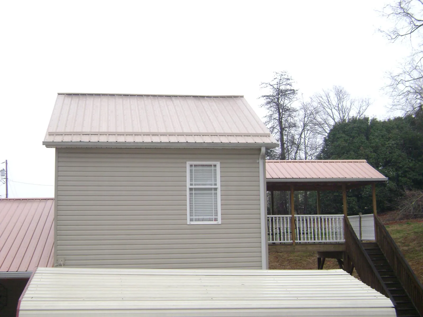 Tan metal roofs on a two story addition and attached porch, from a Roof Replacement job in Sparkill