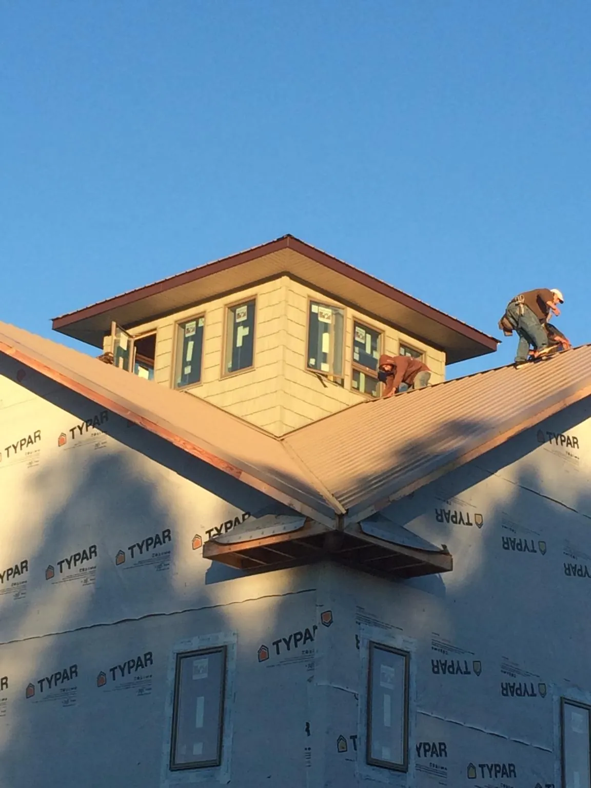 Roofers working around a rooftop cupola on a new metal roof at sunset — Roof Waterproofing in Sparkill by Roofing Brothers